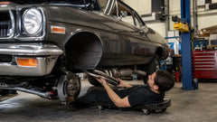 Mechanic fitting stainless steel exhaust headers in a professional garage