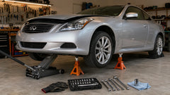 Silver Infiniti G37 is safely lifted on jack stands in a garage.