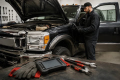 Mechanic diagnosing diesel truck EGR sensor issue with OBD2 scanner