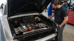 1.Stainless steel exhaust headers installed in a V8 engine bay while a mechanic inspects the fit